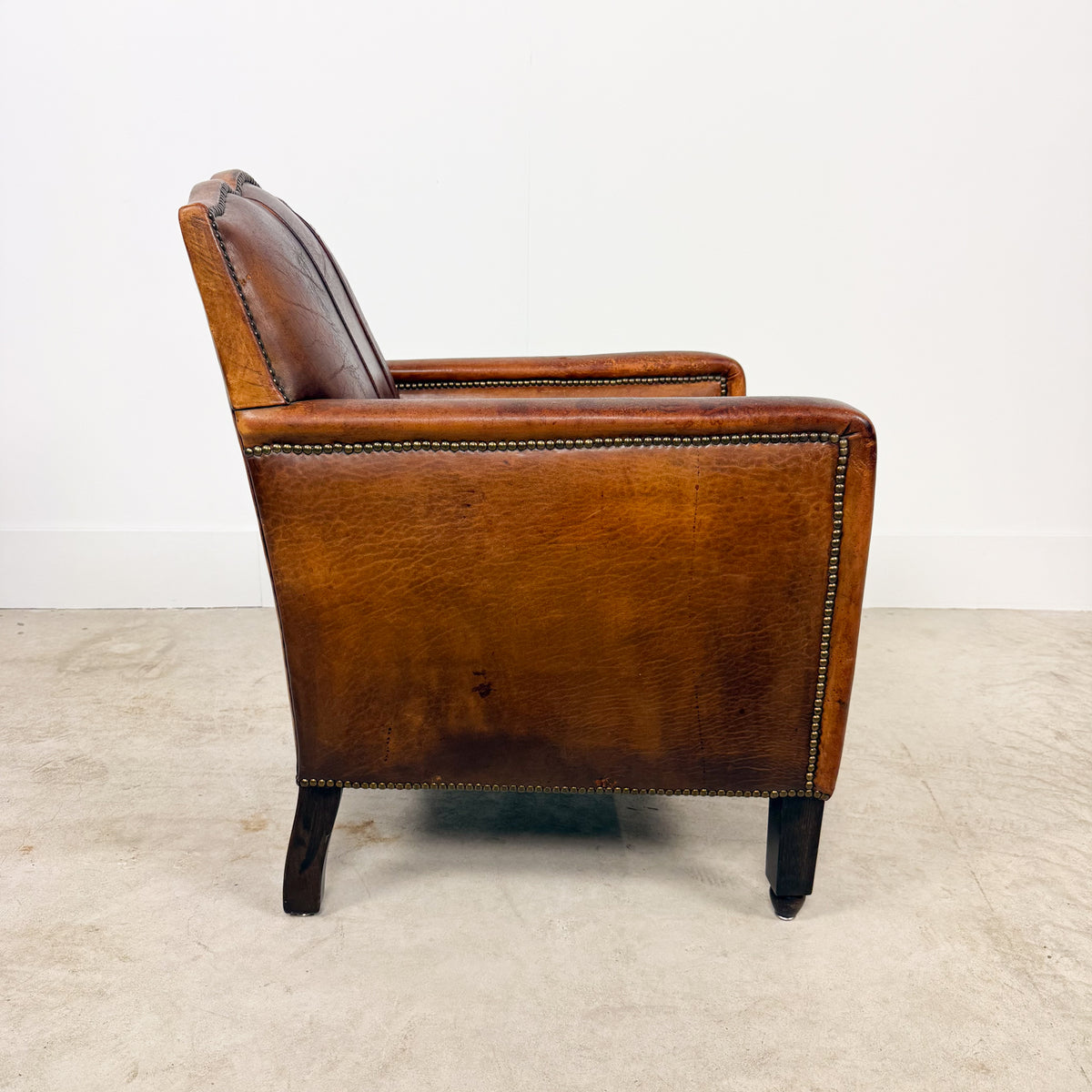 Antique cognac leather club chair with moustache back