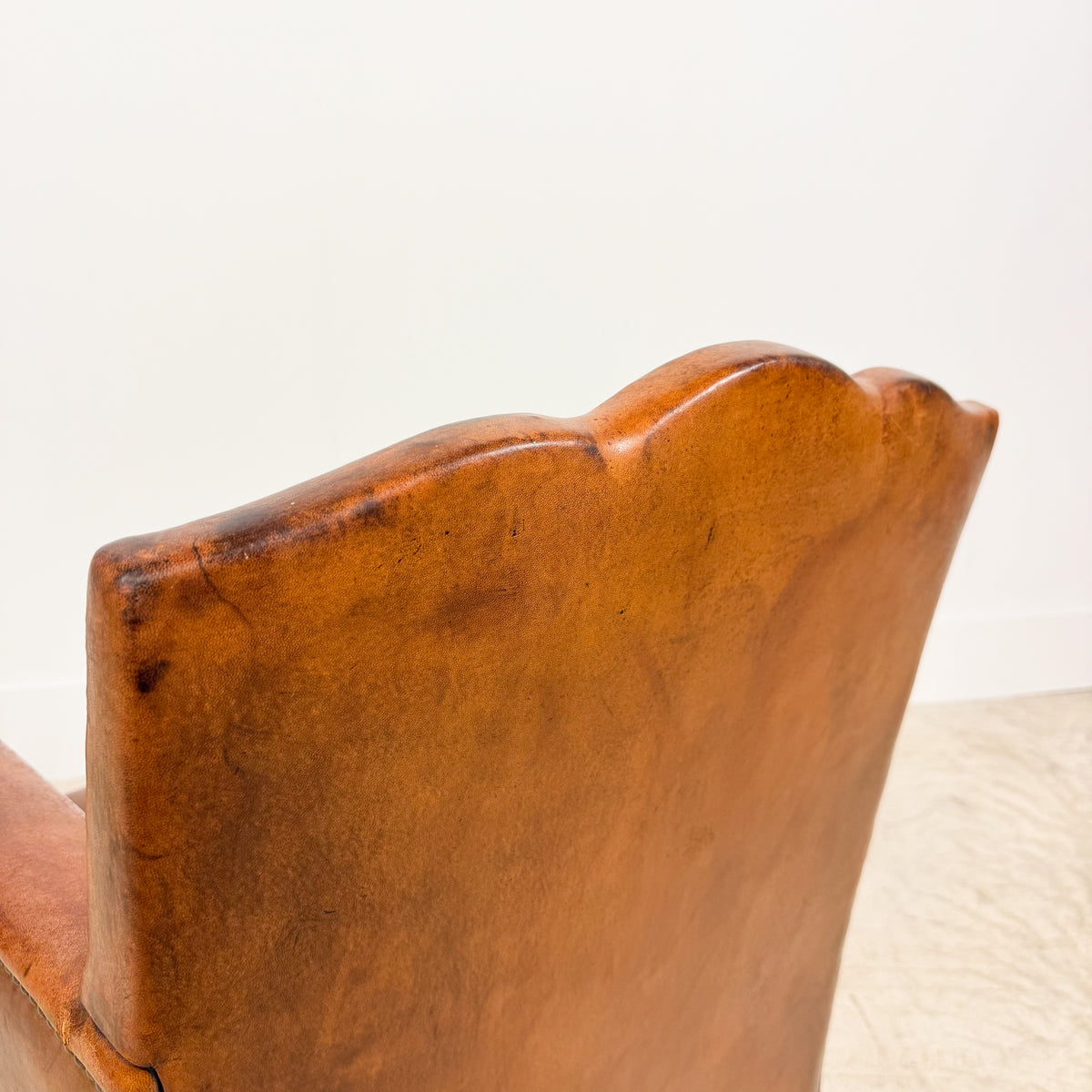 Antique cognac leather club chair with moustache back